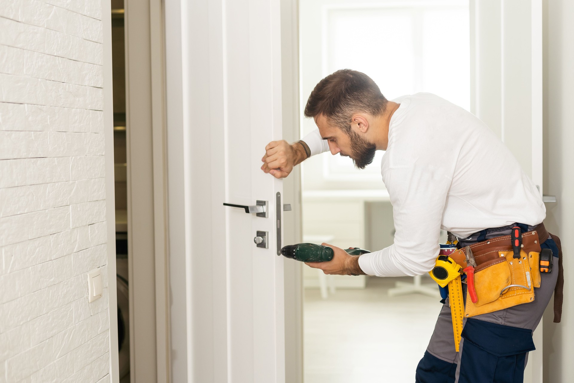  man working as handyman and fixing a door lock in a house entrance