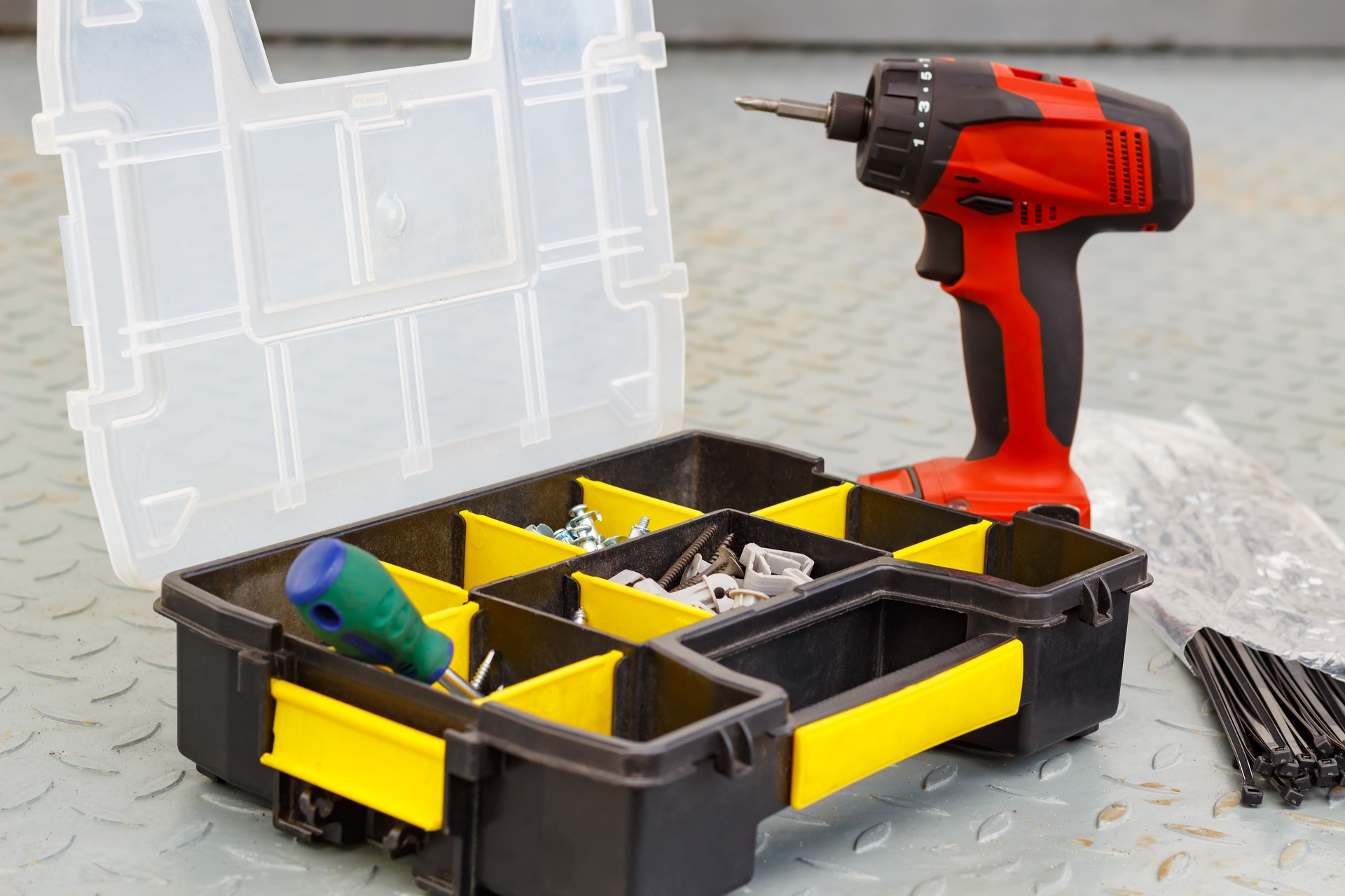 Red cordless screwdriver with screws in a storage box